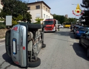 Auto si rovescia sulla carreggiata dopo una carambola con le vetture in sosta